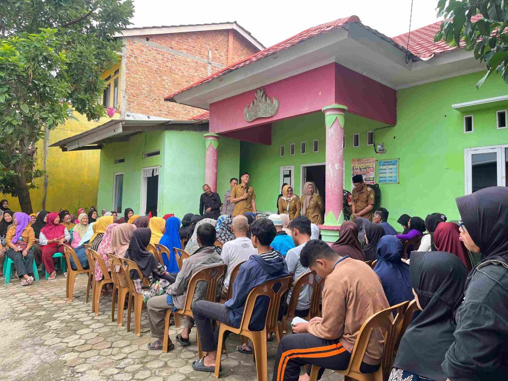 Mahasiswa KKN Kampung Baru bersama perangkat kelurahan membagikan beras bantuan kepada warga.