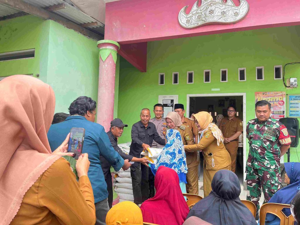 Mahasiswa KKN Kampung Baru bersama perangkat kelurahan membagikan beras bantuan kepada warga.
