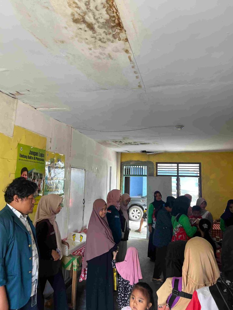 Mahasiswa KKN mendampingi kader Posyandu Lingkungan I dalam kegiatan penimbangan dan pencatatan kesehatan balita.